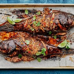 two fish covered in sauce and garnished with herbs