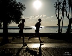 two people running near the water at sunset