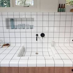 a kitchen with white tiles and wooden cabinets in the center, two sinks are on each side