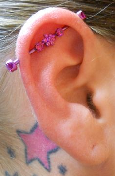 a close up of a person's ear with pink flowers on it