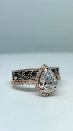 an engagement ring with a pear shaped diamond in the center and filigree band