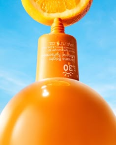 an orange on top of a light fixture with the sky in the backround