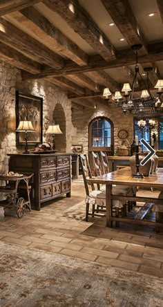 a rustic dining room with stone walls and wood beams, chandelier and table