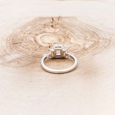 an engagement ring sitting on top of a piece of wood with a diamond in the center