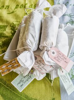 two rolls of food wrapped in white paper with tags on them sitting on a green and yellow table cloth