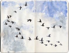 an open notebook with birds flying in the sky and clouds on it's cover