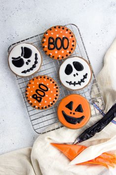 halloween decorated cookies sitting on top of a cooling rack next to an orange and white towel