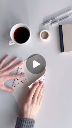 a person holding a video game controller next to a cup of coffee and other items