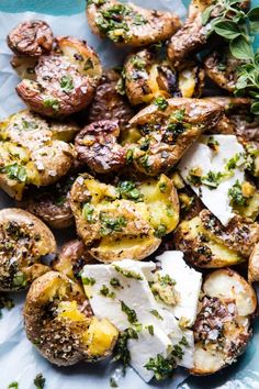 a blue plate topped with potatoes covered in cheese and herbs on top of parchment paper