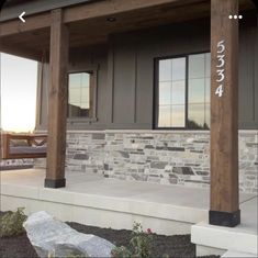 the front porch of a house with stone and wood columns on either side of it