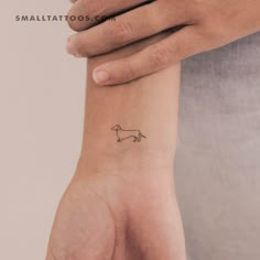 a small tattoo on the wrist of a person with a dog drawn on it's arm