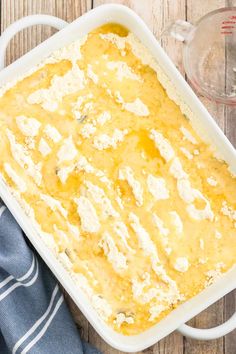 a casserole dish filled with cheese on top of a wooden table next to a blue and white towel