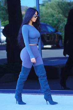 a woman in blue is walking down the street with her leggings and boots