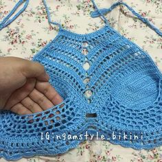 someone is holding their hand out to crochet the top of a blue bra