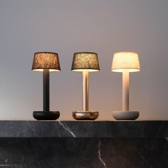 three lamps sitting on top of a table next to each other in front of a wall