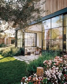 an outside view of a house with lots of windows and flowers in the front yard