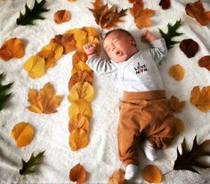 a baby laying on top of a white blanket covered in leaves and fallen down to it's sides