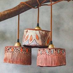 three pink lamps hanging from a tree branch with two birds perched on top of them