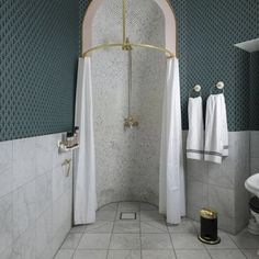 a bathroom with white and blue walls, tile flooring and a gold shower head