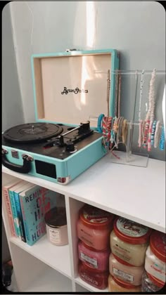 a record player sitting on top of a white shelf next to jars and bracelets