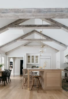 an open kitchen and dining room with wooden beams on the ceiling, white walls and wood flooring