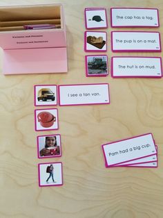 pink cards with pictures and words on them sitting on top of a wooden table next to a box