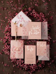 the wedding stationery is laid out on top of pink flowers, and it looks like they