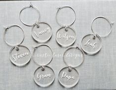 six personalized wine charms with names on them, all in different styles and sizes