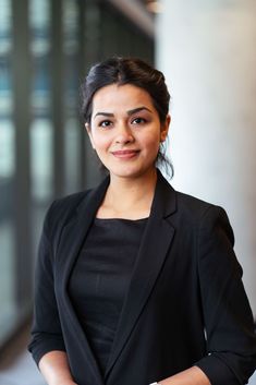 a woman standing in front of a building wearing a black blazer and white bracelet