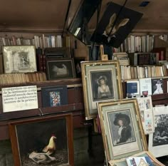 many paintings and pictures are on display in a room with bookshelves full of books