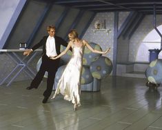 a man and woman are dancing on the dance floor in front of an abstract background