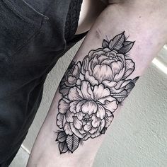 a black and white flower tattoo on the arm