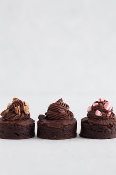 three pieces of chocolate cake sitting next to each other on top of a white table