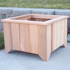 a wooden planter sitting on top of a cement slab next to a grass field