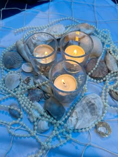 candles are arranged in the shape of a heart surrounded by seashells and pearls