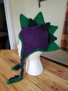 a knitted hat with green leaves and purple flowers