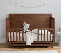 a teddy bear sitting on top of a wooden crib