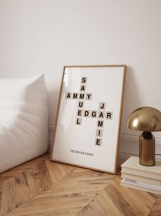 a framed crossword poster sitting on top of a wooden floor next to a lamp