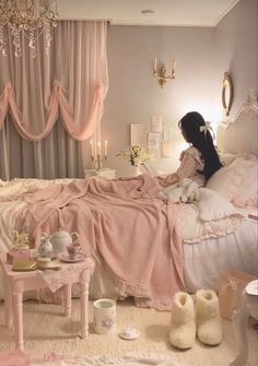 a woman sitting on top of a bed next to a table with a cup and saucer