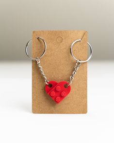 a red heart shaped keychain with two hearts attached to it's sides