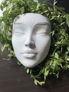 a white mannequin head with green leaves around it's face and eyes