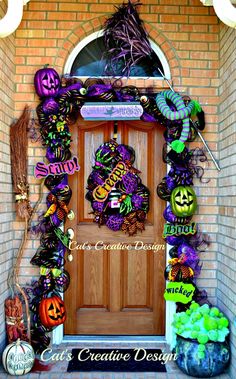 a front door decorated for halloween with decorations on it and pumpkins hanging from the side