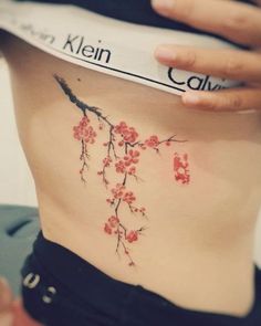 a woman's lower back tattoo with red flowers on her stomach and the word calm written in black ink