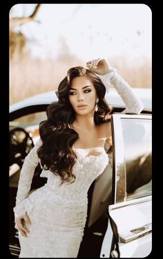 a woman standing next to a car wearing a white dress