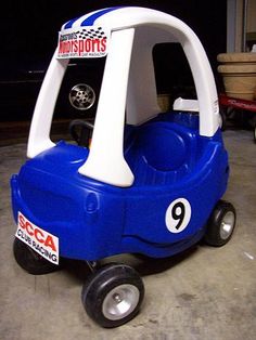 a blue and white toy car sitting on top of a cement floor in a garage