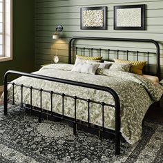 a bedroom with green walls and a black iron bed frame in the middle, along with an area rug on the floor