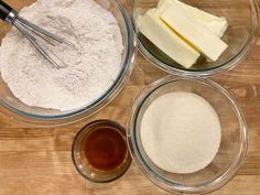 four bowls with different ingredients in them on a wooden counter top, including butter and flour