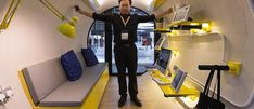 a man standing in the middle of a room filled with yellow and white furniture, holding his arms up