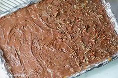 a pan filled with chocolate frosting on top of a metal sheet covered in tin foil