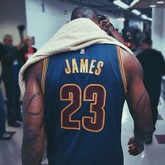 a man in a basketball jersey is talking on his cell phone while walking through an airport